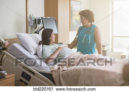 Stock Photo - Doctor talking to pregnant patient in hospital room. Fotosearch