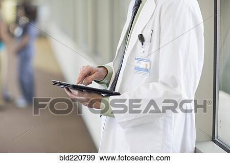 Stock Photo - Doctor using digital tablet in hallway. Fotosearch