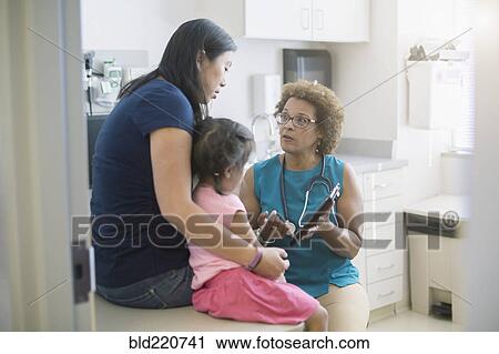 Stock Image - Doctor using digital tablet with patients. Fotosearch