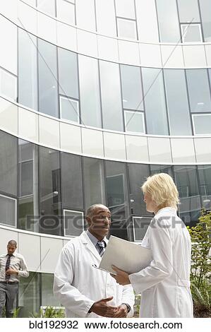 Stock Image - Doctors talking in hospital courtyard. Fotosearch