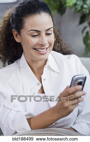 Dominican woman looking at cell phone View Large Photo Image Stock Photo - Dominican woman looking at cell phone. Fotosearch