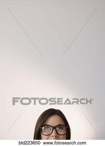 Stock Image - Face of Caucasian woman wearing eyeglasses looking up. Fotosearch