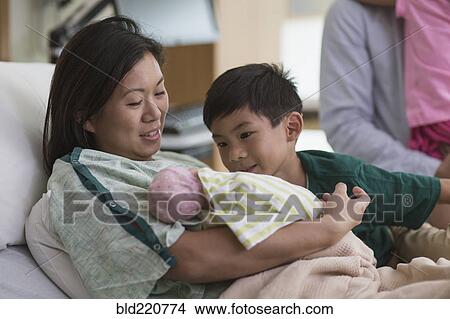 Picture - Family admiring newborn baby in hospital room. Fotosearch