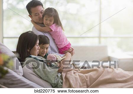 Stock Photography - Family admiring newborn baby in hospital room. Fotosearch
