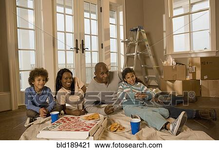 Stock Image - Family eating on floor in new home. Fotosearch