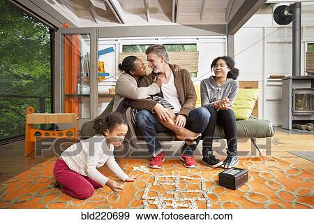 Stock Photo - Family hugging in living room. Fotosearch