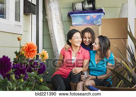 Stock Image - Family hugging outside house. Fotosearch
