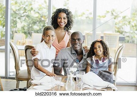 Family smiling at restaurant table View Large Photo Image Stock Photograph - Family smiling at restaurant table. Fotosearch