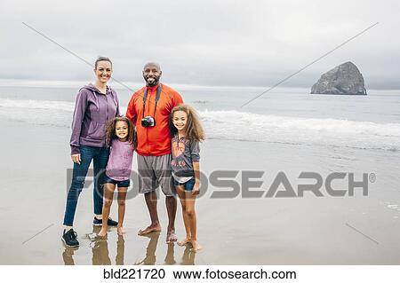 Stock Image - Family smiling on beach. Fotosearch