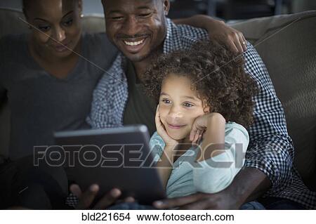 Family using digital tablet on sofa View Large Photo Image Picture - Family using digital tablet on sofa. Fotosearch