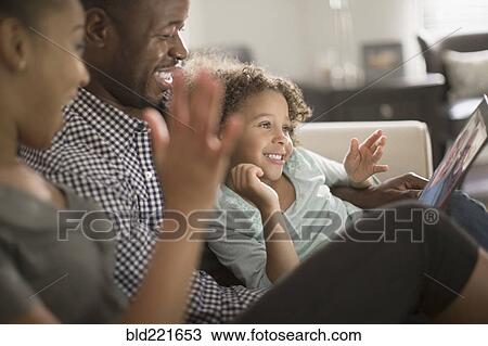 Stock Image - Family using digital tablet on sofa. Fotosearch
