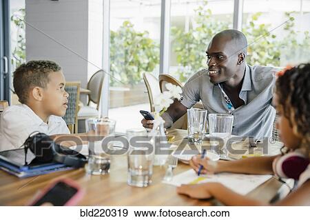 Stock Photo - Father and children eating in restaurant. Fotosearch
