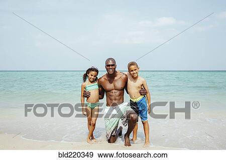 Stock Photo - Father and children hugging on beach. Fotosearch