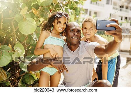Father and children taking selfie with cell phone outdoors View Large Photo Image Stock Image - Father and children taking selfie with cell phone outdoors. Fotosearch