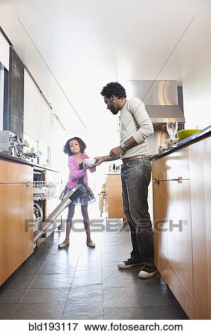 Stock Photo - Father and daughter loading dishwasher. Fotosearch