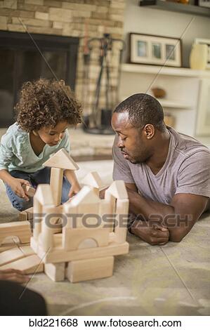 Stock Photo - Father and daughter playing with building blocks in living room. Fotosearch
