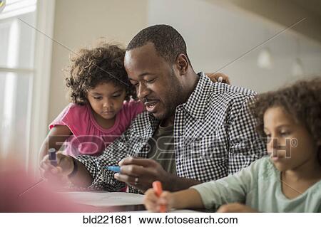 Stock Image - Father and daughters drawing at table. Fotosearch