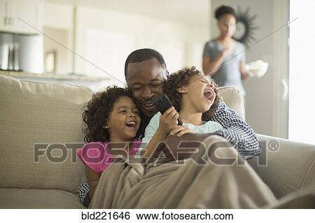 Stock Photograph - Father and daughters playing on sofa. Fotosearch