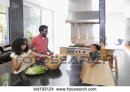 Picture - Father and daughters preparing food in kitchen. Fotosearch