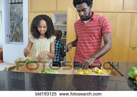 Stock Photography - Father and daughters preparing food in kitchen. Fotosearch
