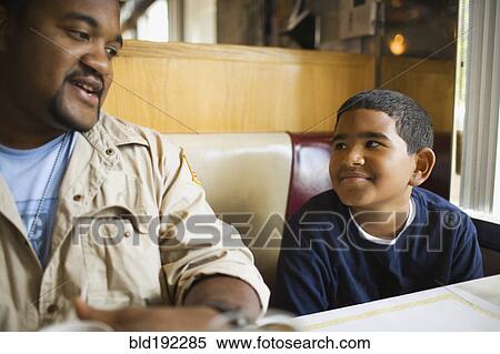 Stock Photography - Father and son sitting at diner booth. Fotosearch