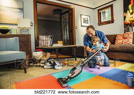 Stock Image - Father and son vacuuming living room. Fotosearch