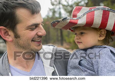 Stock Photograph - Father carrying daughter in patriotic hat. Fotosearch