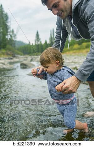 Father helping daughter walk in river View Large Photo Image Stock Photo - Father helping daughter walk in river. Fotosearch