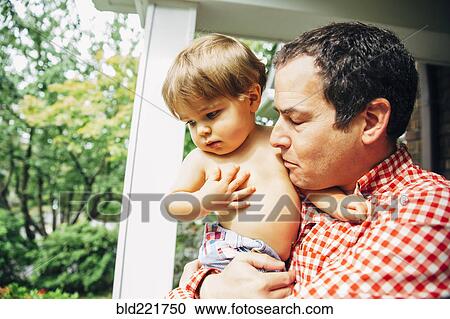 Stock Image - Father holding son on porch. Fotosearch