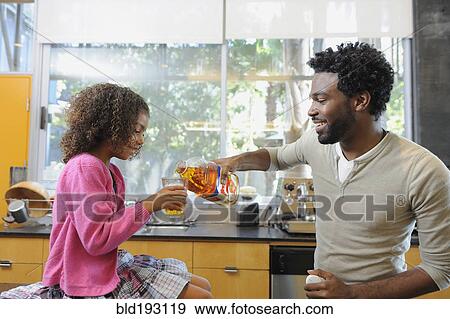 Stock Photo - Father pouring juice for daughter. Fotosearch