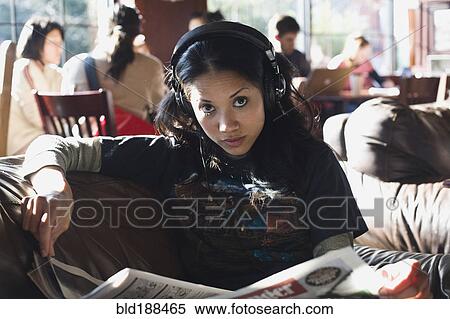 Stock Photography - Filipino woman listening to headphones in coffee shop. Fotosearch