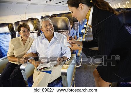 Stock Photo - Flight attendant helping couple on airplane. Fotosearch