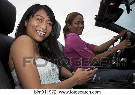 Stock Image - Friends driving in convertible. Fotosearch
