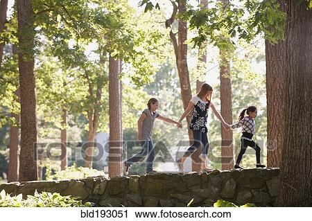 Friends holding hands and walking on stone wall View Large Photo Image Stock Image - Friends holding hands and walking on stone wall. Fotosearch