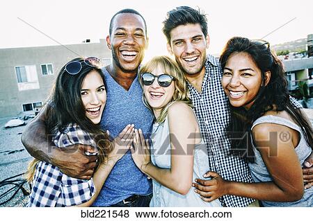 Stock Photo - Friends hugging on urban rooftop. Fotosearch