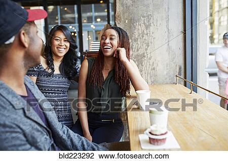 Stock Image - Friends laughing in coffee shop. Fotosearch
