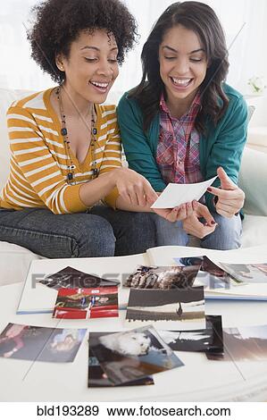 Friends looking at old photographs together View Large Photo Image Stock Photo - Friends looking at old photographs together. Fotosearch