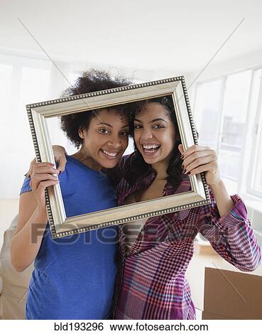 Stock Photograph - Friends looking through empty frame. Fotosearch