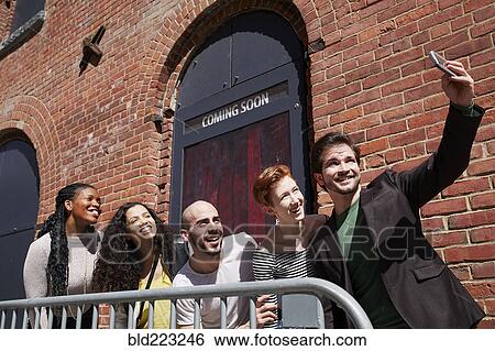 Stock Photograph - Friends posing for selfie behind railing. Fotosearch