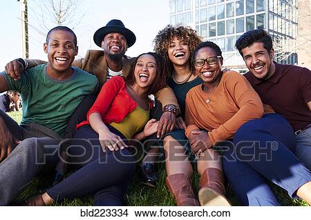 Picture - Friends sitting in grass and laughing. Fotosearch