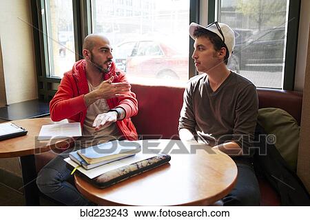 Stock Image - Friends talking in cafe booth. Fotosearch
