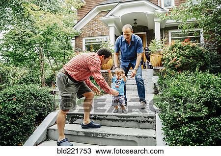 Stock Image - Gay fathers and baby son on steps. Fotosearch