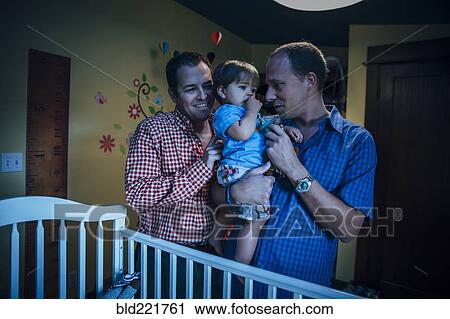 Gay fathers holding baby son in nursery View Large Photo Image Stock Image - Gay fathers holding baby son in nursery. Fotosearch