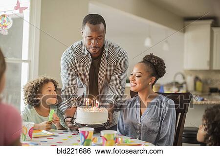 Stock Photograph - Girl admiring birthday cake at party. Fotosearch