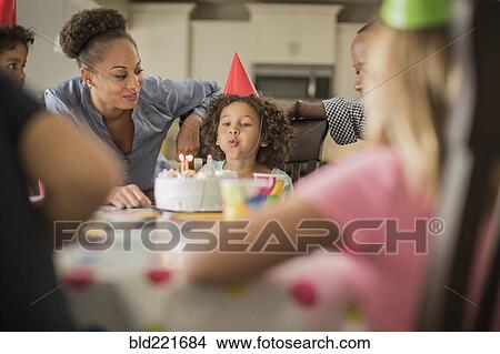 Picture - Girl blowing birthday candles at party. Fotosearch