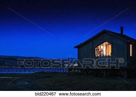 Stock Photo - Glowing house and dock over remote lake. Fotosearch
