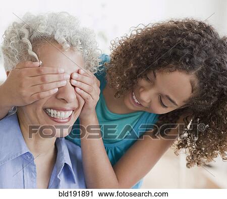 Stock Image - Granddaughter covering grandmother's eyes. Fotosearch