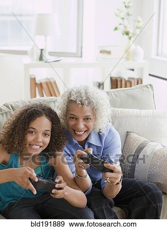 Grandmother and granddaughter playing video game View Large Photo Image Stock Photo - Grandmother and granddaughter playing video game. Fotosearch