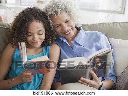 Stock Photography - Grandmother and granddaughter reading on sofa. Fotosearch
