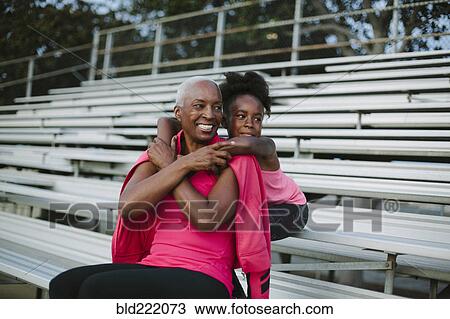 Stock Image - Grandmother and granddaughter sitting on bleachers. Fotosearch